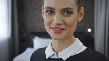 Neşeli hizmetçi otel odasındaki kameraya bakıyor.