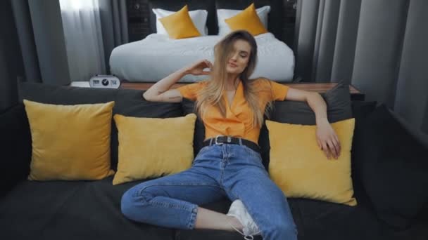 現代のホテルの部屋でソファで凍える陽気な女性 — ストック動画