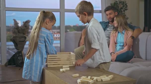 Братья Сёстры Упаковывают Деревянные Блоки Игры Коробку Родителями Заднем Плане — стоковое видео