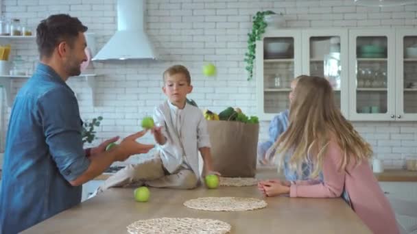 Glimlachende Vader Jongleren Met Groene Appels Terwijl Familie Applaudisseren Keuken — Stockvideo