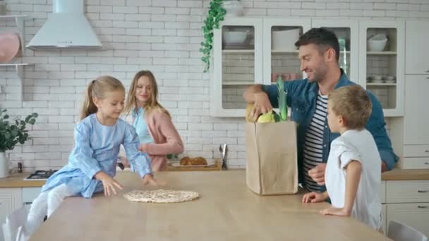 Sonriente Padre Desembalaje Bolsa Compras Con Comestibles Mesa Cerca Familia — Vídeos de Stock