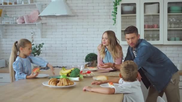 Dottern Pekar Med Handen Smörgåsar Medan Föräldrarna Pratar Köket — Stockvideo