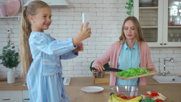 Lycklig Dotter Med Smartphone Tar Foto Mamma Förbereda Sallad Köket — Stockvideo