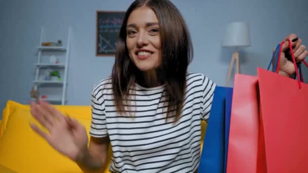 Szczęśliwa Młoda Kobieta Pokazując Torby Zakupy Podczas Rozmowy Wideo Domu — Wideo stockowe