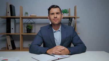 İş adamı heyecanlanıyor ve ofisteki video görüşmesi sırasında evet işareti yapıyor.