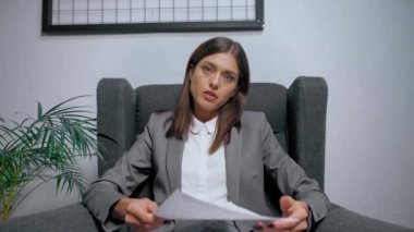 Ofisteki Skype görüşmesi sırasında iş kadını başını sallıyor ve grafiklerle kağıtları gösteriyor.