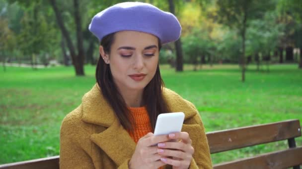 在公园里用智能手机发送语音讯息的微笑女人 — 图库视频影像