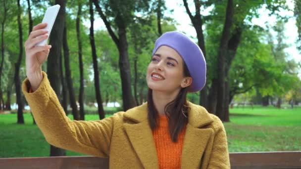 快乐的女人穿着时髦的秋装 在公园里用智能手机自拍 — 图库视频影像