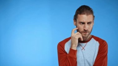 Düşünen adam, fikir jesti yapan ve mavi üzerine izole edilmiş bir şekilde gülümseyen.
