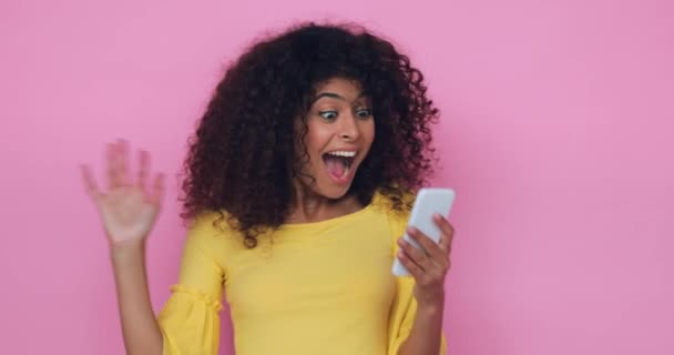 Изумленная Молодая Женщина Смотрит Смартфон Изолирован Розовый — стоковое видео