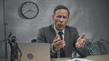 Sigorta acentesi ofiste dizüstü bilgisayarın yanında kamerayla konuşuyor. 