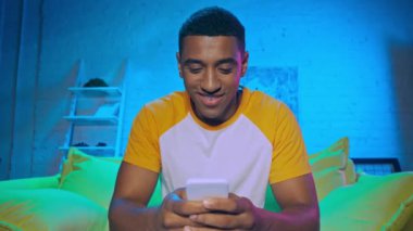 Akıllı telefon kullanan ve patlamış mısır yiyen Afrikalı Amerikalı bir adam. 
