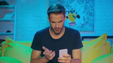 Akıllı telefon kullanıp bira içen üzgün bir adam. 