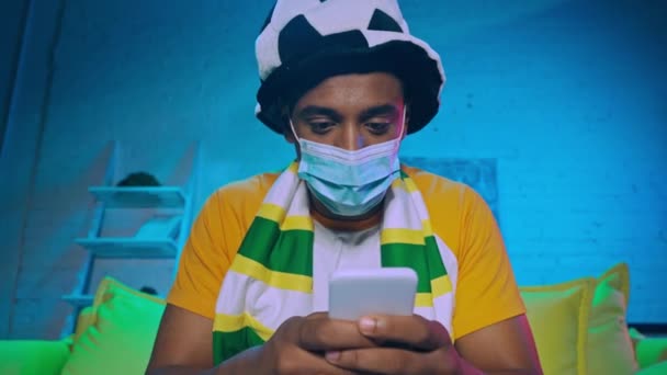 Αφροαμερικανός Ποδοσφαιρόφιλος Ιατρική Μάσκα Που Δείχνει Ναι Και Χρησιμοποιεί Smartphone — Αρχείο Βίντεο
