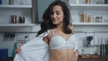 İç çamaşırlı seksi kadın gömleğini çıkarıp mutfakta kameraya atıyor.