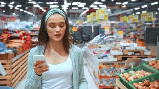 Jonge Vrouw Checkt Lijst Smartphone Tijdens Het Wandelen Supermarkt — Stockvideo