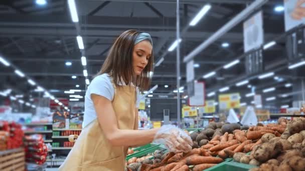 スーパーでニンジンを集めるエプロンの若いマーチャンダイザー — ストック動画