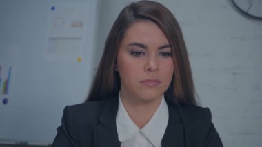 Hoşnutsuz iş kadını yanakları şişirip kameraya bakıyor.