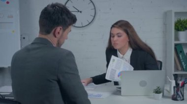 Çizelgeleri tutan ve yöneticiye veda jesti gösteren üzgün iş kadını.