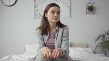 Pijamalı genç ve endişeli bir kadın hamilelik testi sonuçlarını bekliyor. 