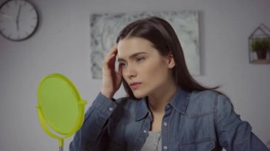 Sivilce sıkan ve aynaya bakan hoşnutsuz kadın