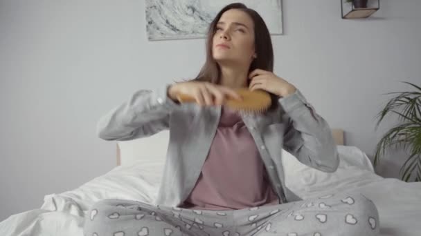 Νεαρή Μελαχρινή Γυναίκα Κάθεται Στο Κρεβάτι Και Βούρτσισμα Των Μαλλιών — Αρχείο Βίντεο