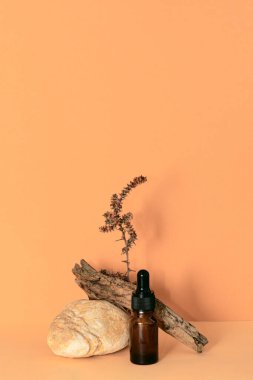 Modayı takip eden pastel kahverengi arka planda gerekli yağ ya da serumdan oluşan damlatan cam şişe. Doğal organik kozmetik. Asgari düzeyde. Uzayı kopyala Dikey yönelim