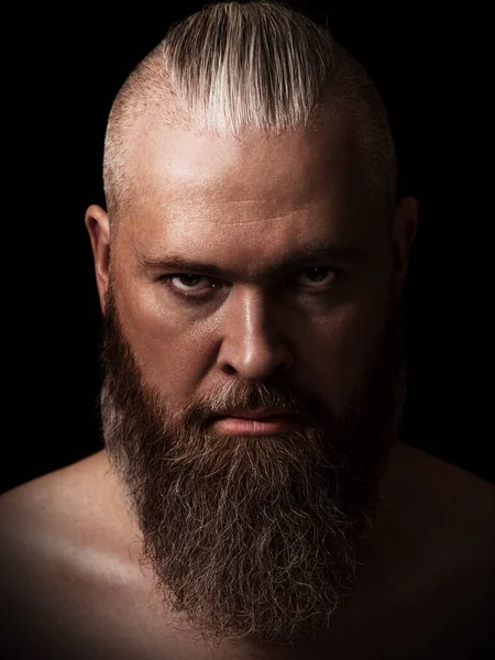 stock image Handsome brutal caucasian bearded man in the dark. Studio portrait. Low key. Closeup. Vertical orientation