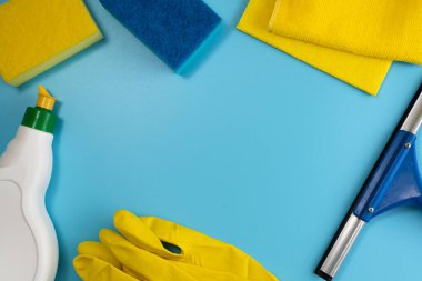Ev temizleme malzemelerinin en üst görüntüsü: lastik eldivenler, süngerler, kumaşlar, mavi arka planda cam sileceği ve deterjan. Uzayı kopyala Düz yatıyordu