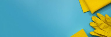 Sarı koruyucu eldivenler, sünger ve kumaşlar mavi arka planda. Temizlik malzemelerinin en üst görüntüsü. Pankart. Uzayı kopyala Bahar evi temizlik konsepti