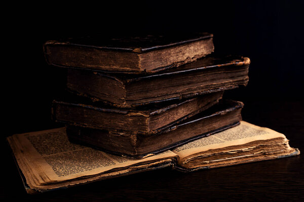 Stack of old worn shabby jewish books in leather binding on the open pages of Machzor in the dark. Closeup. Selective focus. Low key