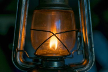 Vintage kerosene lamp with fire inside and glass bulb in dark
