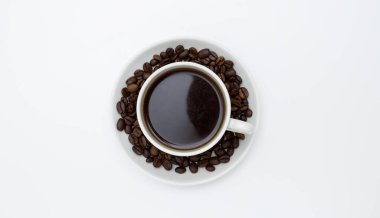 Beyaz fincan ve kahve ve kahve çekirdekli çay tabağı. Üst manzara, beyaz arkaplan. Metin için boş alan.