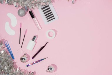 Kirpik uzatma ustaları için yeni yıl ve Noel. Kirpikçiler ve takma kirpiklerle ilgili şeyler. Üst görünüm, pembe arkaplan, metin için boş alan.
