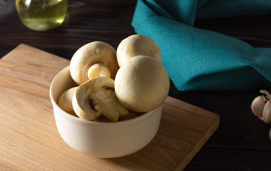 Tahta bir tahtanın üzerinde beyaz bir tabakta tüm şampiyon. Sağlıklı vejetaryen yemekleri. Yemek pişirmek için gerekli malzemeler.