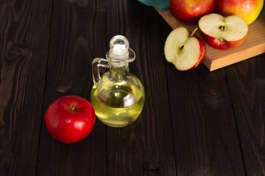 Elma şarabı sirkesi. Koyu ahşap bir masada cam bir sürahide. Elmalar yakında. Boş alan.