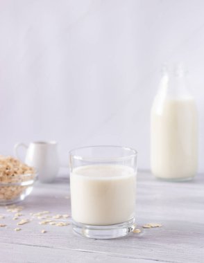 Hafif arka planda cam bir fincanda sebze yulaf sütü. Sağlıklı içecekler, vejetaryenlik. Yan görüş. Dikey fotoğraf