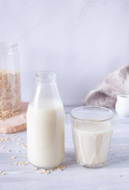 Cam şişede sebze yulaf sütü ve arka planda cam bardak. Sağlıklı içecekler, vejetaryenlik. Yan görüş. Dikey fotoğraf