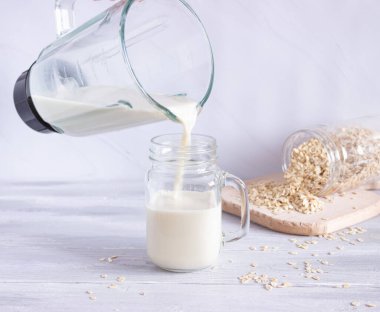 Sebze yulaf sütü blenderdan cam bardağa dökülür. Bitkisel sütün hazırlanması. Sağlıklı içecekler, vejetaryenlik. Yan görünüm.