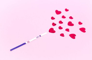 Pozitif bir hamilelik testi şeridi ve kırmızı kalpler. Gebelik kavramı, bir çocuğun beklentisi, bir aile..