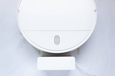 Beyaz robot elektrik süpürgesi ve şarj aleti parçası..