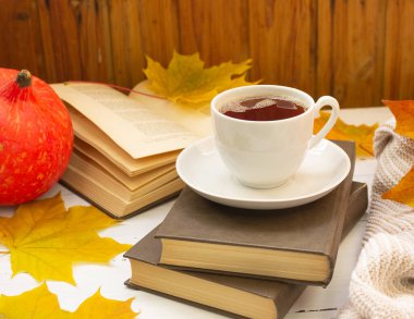 Sonbahar atmosferi. Bir fincan çay, sarı akçaağaç yaprağı, kitaplar ve örgü bir şey.