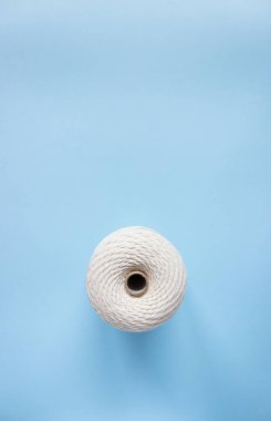 A skein of white cotton cord on a blue background, free space.