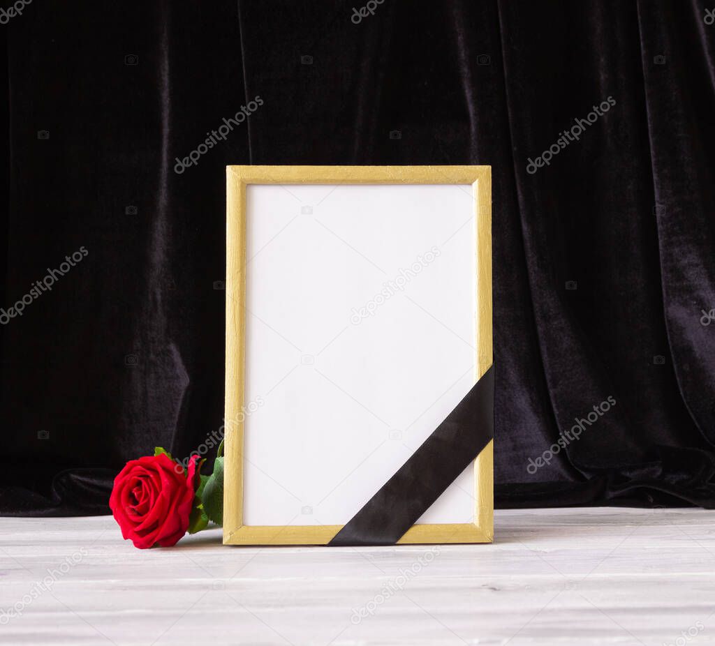 The concept of memory, funerals and condolences. Photo frame with black mourning ribbon and flower.