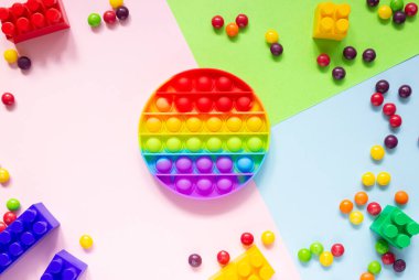 Renkli anti-stres oyuncağı, renkli arka planda yuvarlak şekilli, üst görünüm. Şeker fıçıları yakında.