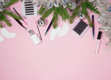 Kirpik uzatma ustaları için yeni yıl ve Noel. Kirpikçiler, takma kirpikler, cımbızlar, taraklar, uzatılmış kirpikler için fırçalar. Üst görünüm, pembe arkaplan, metin için boş alan.
