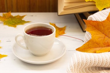 Sonbahar atmosferi. Bir fincan çay, sarı akçaağaç yaprağı, kitaplar ve örgü bir şey.