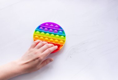 Renkli anti-stres oyuncağı yuvarlak şekilli ve ellerle patlar. Ellerin iyi motor becerilerini geliştirir. Metin için boş alan.