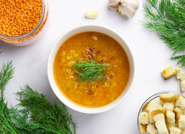 Red lentil soup with ingredients on a light background. Traditional Turkish or Arabic spicy lentil and vegetable soup, healthy vegan food. Top view.