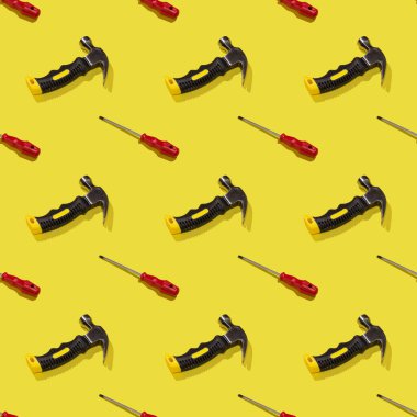 Sarı arka planda çekiçler ve tornavidalar, desenler, sert gölgeler. İnşaat aletleri, tamirat. Tasarım için arkaplan.